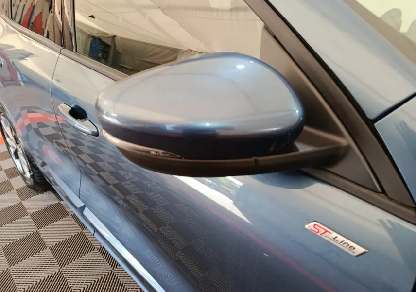 Rétroviseur côté gauche et badge ST Line sur la porte d’un Ford Kuga bleu vu en léger plongée.