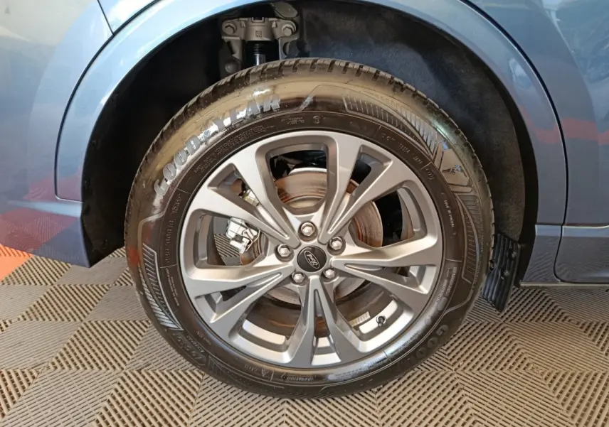 Gros plan sur la roue avant droite du Ford Kuga bleu 2024 avec jante alliage et pneu Goodyear visible.