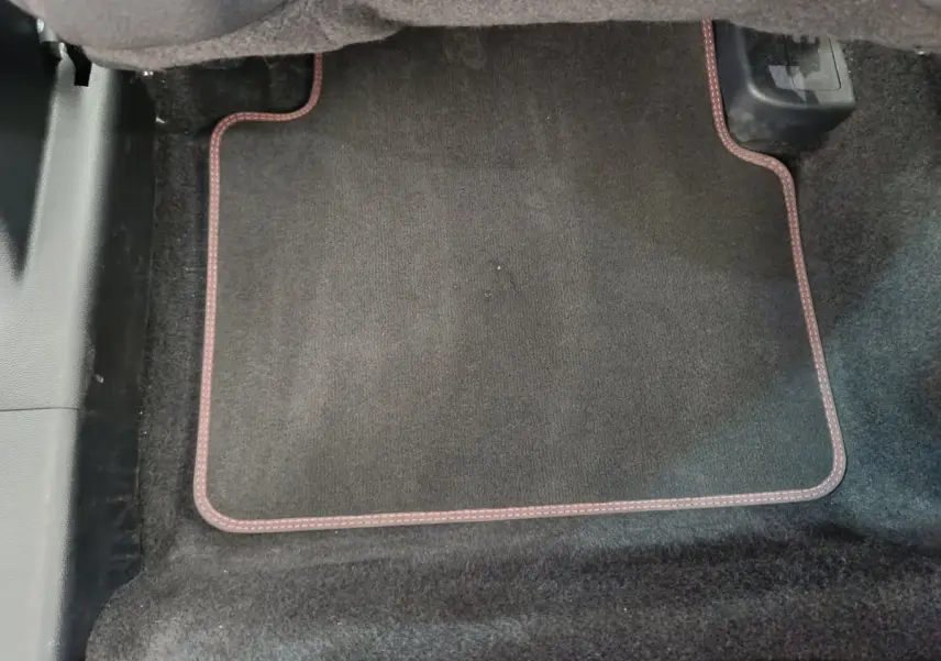 Tapis de sol noir avec surpiqûres rouges dans l'habitacle avant d'un Ford Kuga bleu 2024.