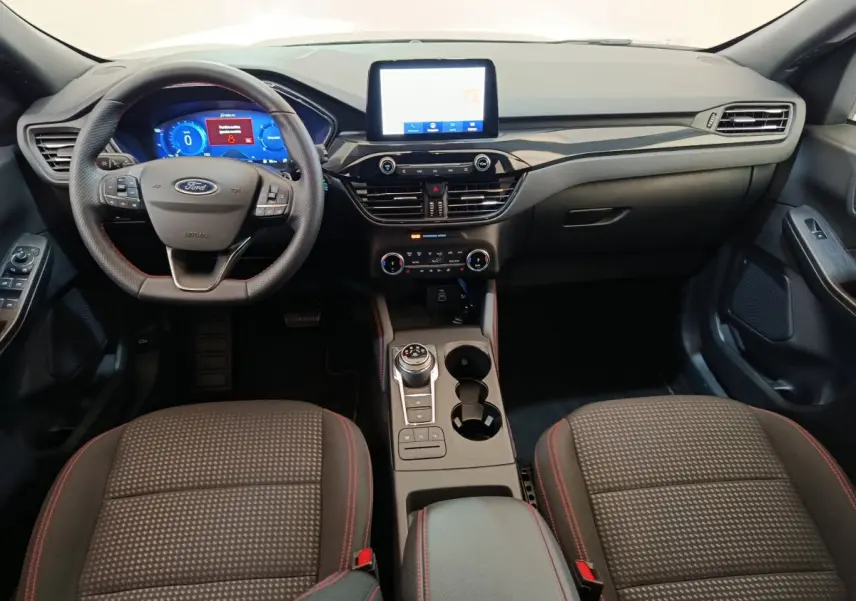 Intérieur du Ford Kuga 2024 St Line, vue avant du tableau de bord avec écran tactile et volant multifonctions noir.