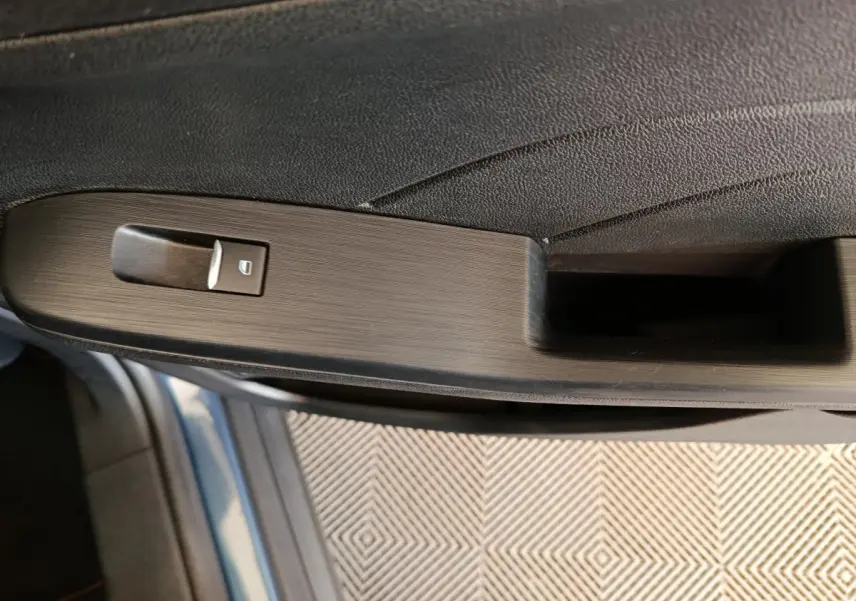 Détail de la commande de lève-vitre côté conducteur sur la porte intérieure d'un Ford Kuga bleu 2024.
