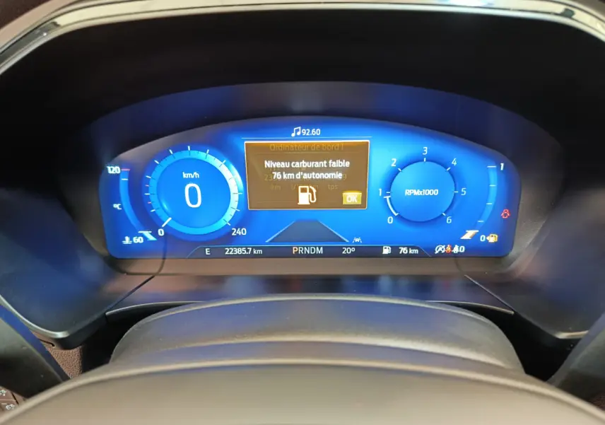 Tableau de bord numérique bleu du Ford Kuga 2024 affichant un avertissement de carburant faible et la vitesse à zéro