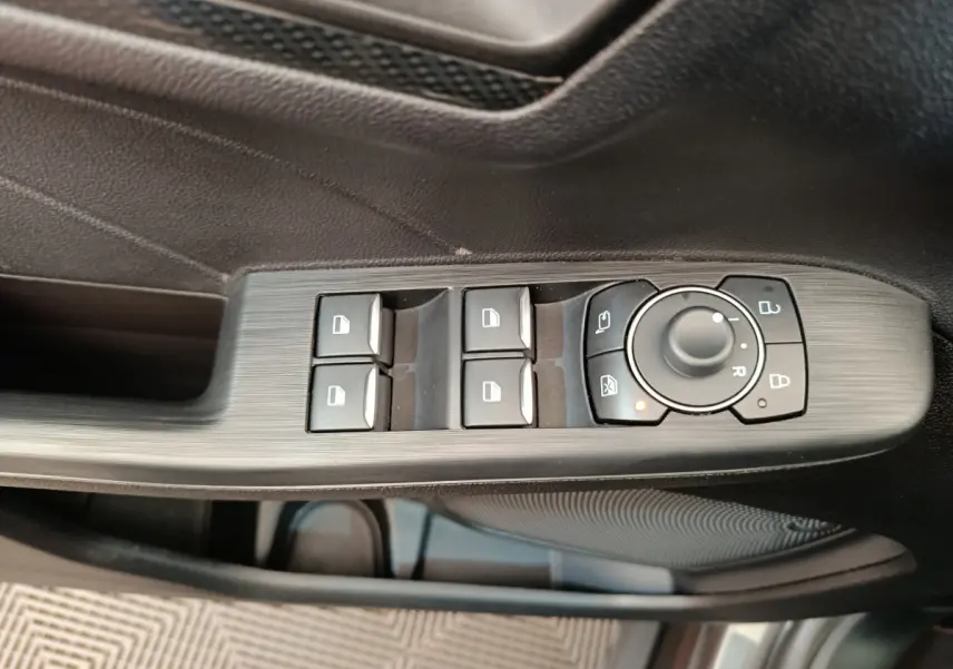 Gros plan sur les commandes de lève-vitres et rétroviseurs côté conducteur du Ford Kuga gris clair 2024 St Line.