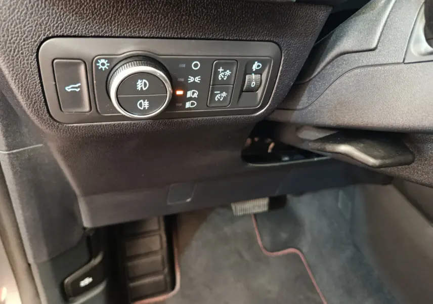 Gros plan sur les commandes d'éclairage et ouverture de coffre côté gauche du tableau de bord noir du Ford Kuga gris clair 2024.