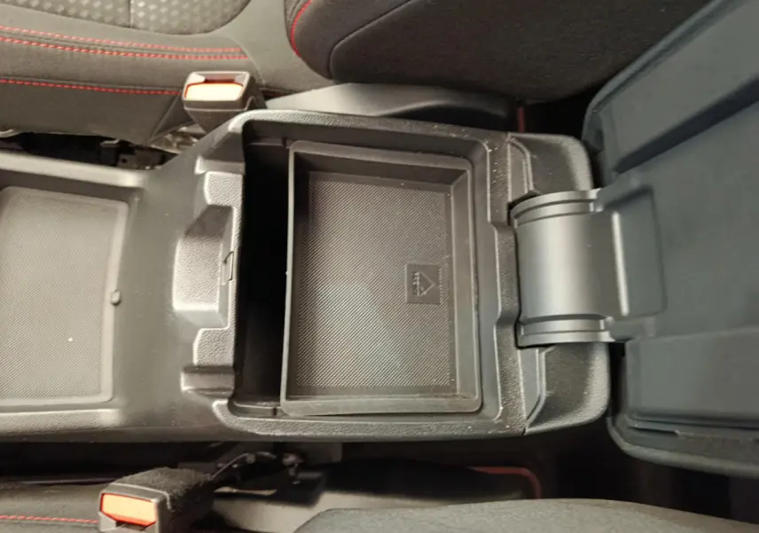 Vue plongeante sur le rangement central ouvert du Ford Kuga gris clair, avec surpiqûres rouges visibles sur les sièges noirs.