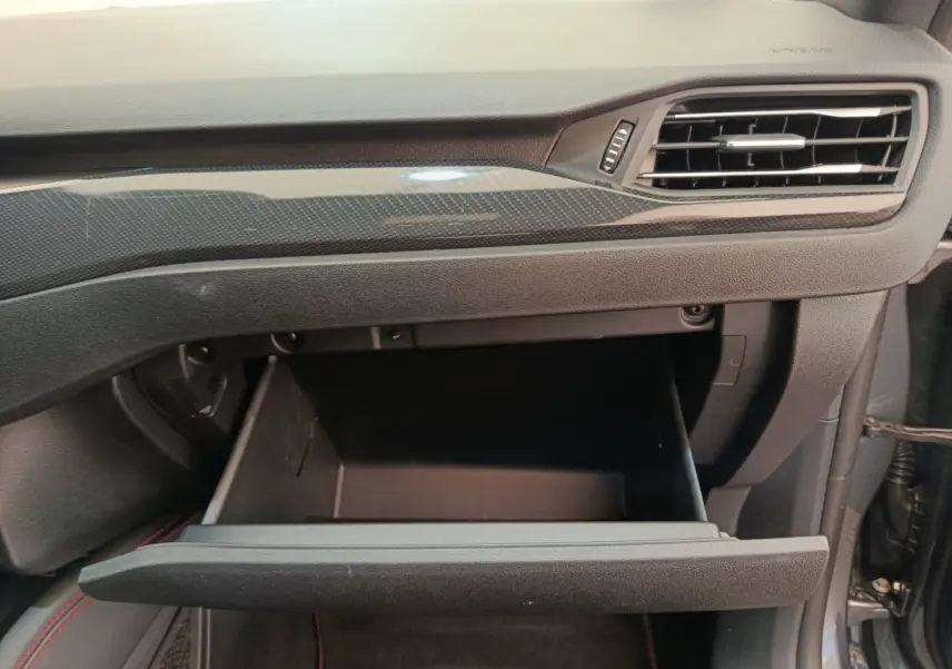 Vue rapprochée de la boîte à gants ouverte côté passager du Ford Kuga 2024 avec tableau de bord gris et insert carbone.