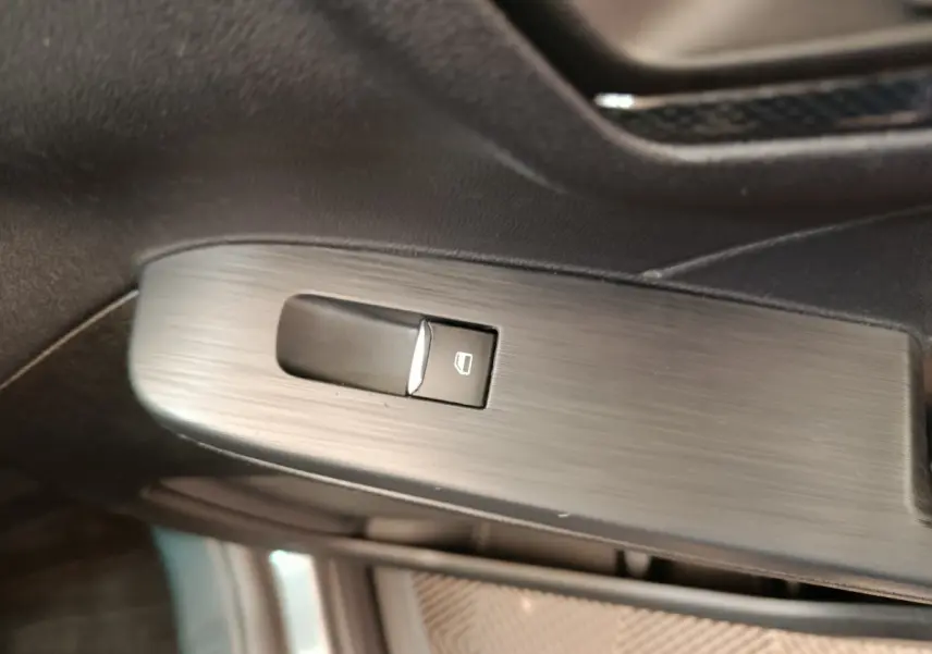 Bouton de commande de lève-vitre électrique sur la porte intérieure côté conducteur du Ford Kuga gris clair 2024 St Line.