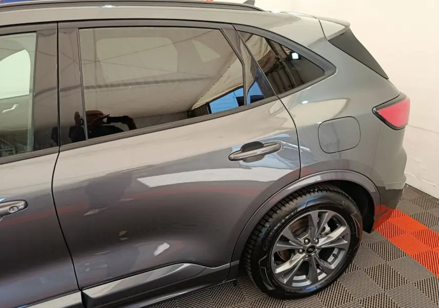 Vue côté droit arrière du Ford Kuga 2024 gris clair, mettant en valeur la porte arrière et la roue alliage.