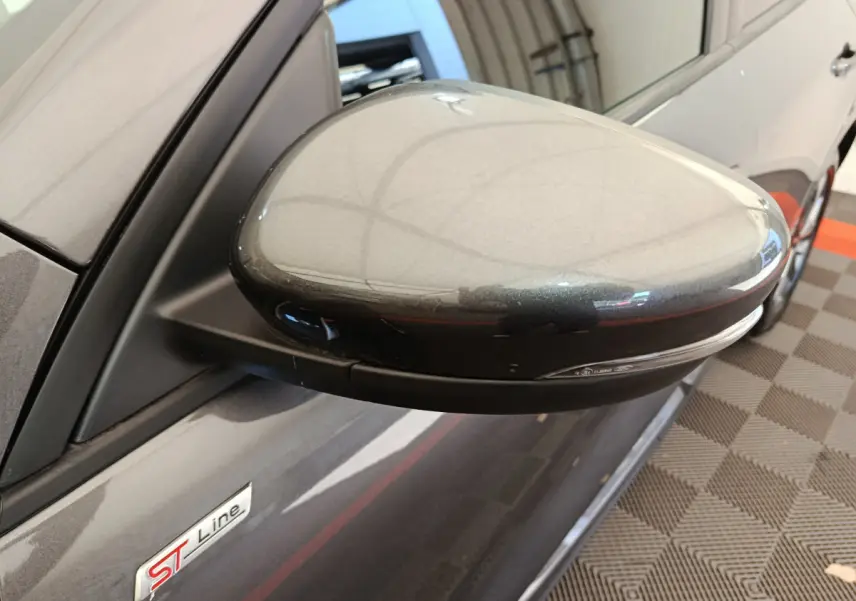 Gros plan sur le rétroviseur côté gauche gris clair du Ford Kuga 2024 version ST Line avec logo ST visible sur la portière.