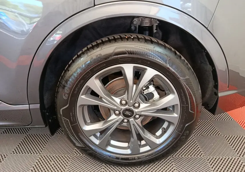 Gros plan sur la roue avant gauche du Ford Kuga gris clair 2024 avec jante alliage et pneu Goodyear.
