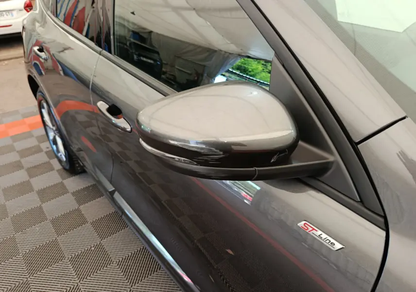 Vue rapprochée côté gauche du rétroviseur gris clair et de l'emblème ST Line sur une Ford Kuga 2024.