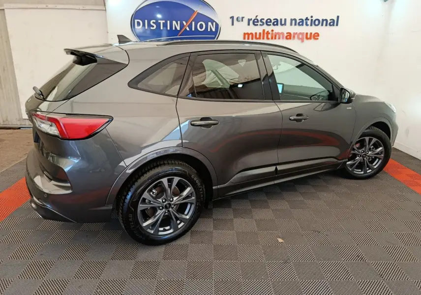 Ford Kuga 2024 gris clair vue de profil côté droit, avec jantes alliage et vitres teintées dans un showroom