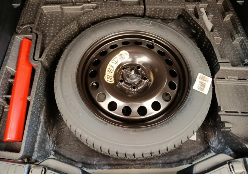 Vue plongeante sur la roue de secours noire et le logement gris foncé du coffre du Ford Kuga gris clair 2024 St Line