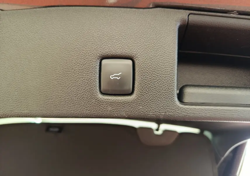 Bouton d'ouverture électrique du coffre sur la garniture intérieure arrière du Ford Kuga gris clair 2024.