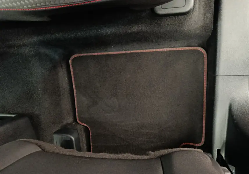 Tapis de sol noir avec surpiqûres rouges côté passager arrière d'un Ford Kuga 2024 gris clair St Line.