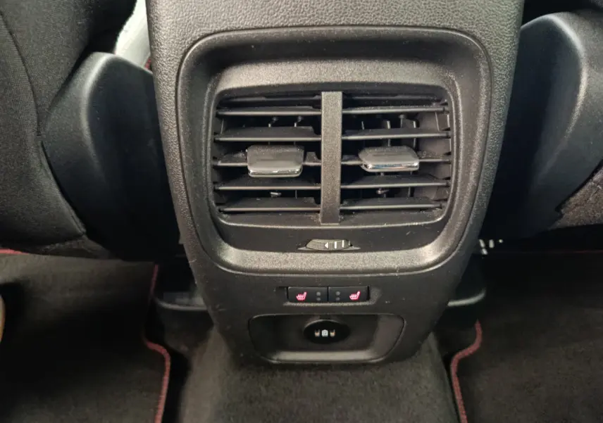 Gros plan sur la console arrière noire du Ford Kuga 2024 avec aérateurs, commandes de sièges chauffants et prise USB.