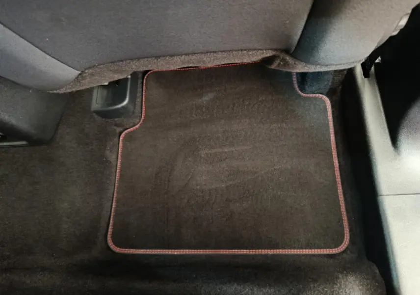 Tapis de sol noir avec surpiqûres rouges sous le siège arrière du Ford Kuga gris clair 2024 St Line.