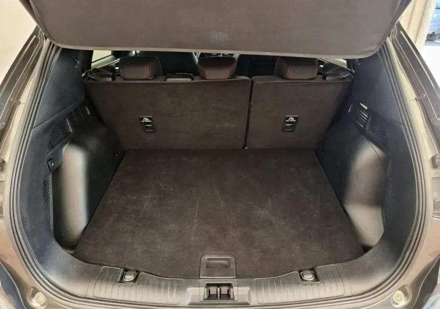 Coffre spacieux ouvert du Ford Kuga gris clair 2024, avec banquette arrière en tissu noir et finitions sobres.