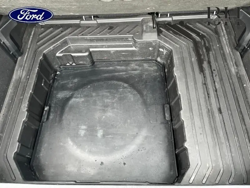 Coffre ouvert en vue plongeante du Ford Puma 2023, montrant le compartiment de rangement noir sous le plancher.