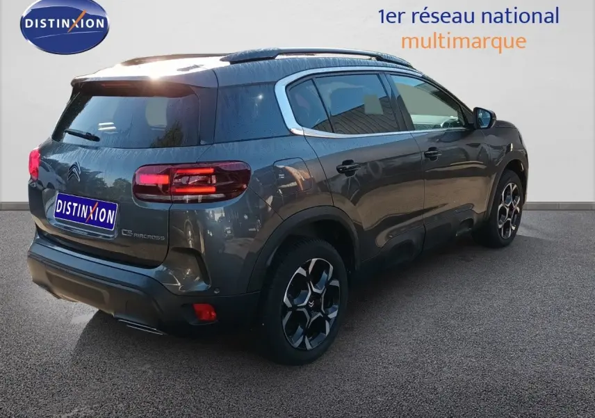 Vue 3/4 arrière droite du Citroën C5 Aircross gris platinium métal avec jantes bi-ton et feux LED allumés.