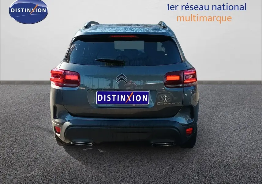 Vue arrière d'un Citroën C5 Aircross gris platinium métal avec feux allumés sur fond neutre.