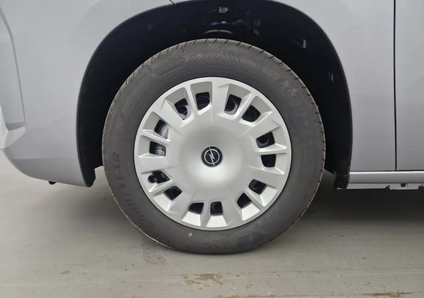 Gros plan sur la roue avant gauche grise d'un Opel Combo Life M 1.5 BlueHDi avec enjoliveur blanc et logo Opel.