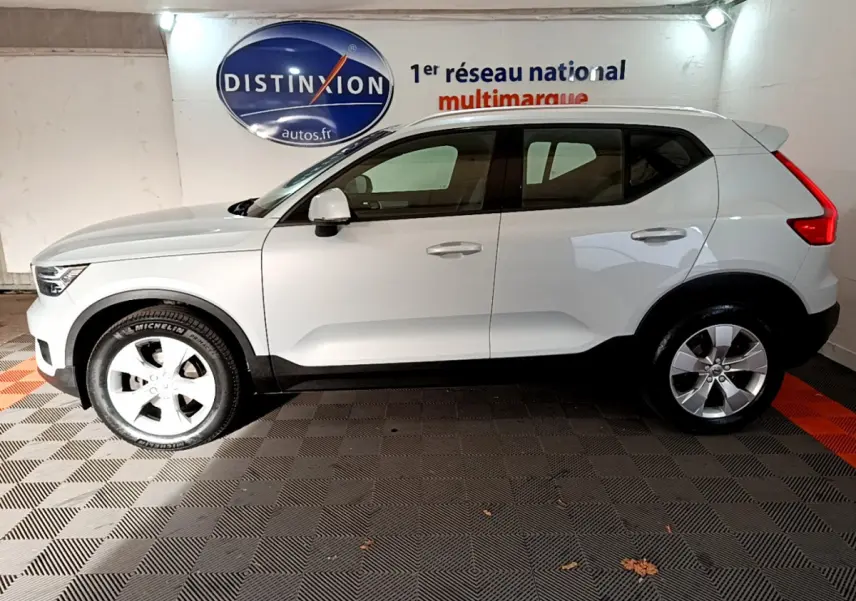 Vue latérale droite d'un Volvo XC40 gris clair garé en intérieur avec jantes alliage et toit blanc.