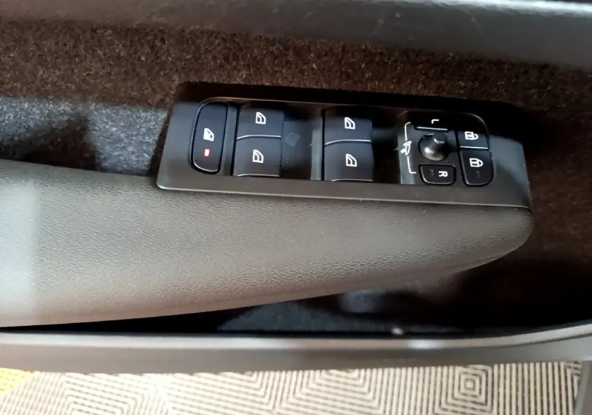Gros plan sur les commandes des vitres et rétroviseurs sur la porte côté conducteur du Volvo XC40 gris clair.