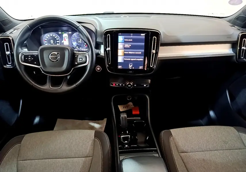 Vue intérieure avant du Volvo XC40 T2 Momentum 2020, tableau de bord noir avec écran tactile central et volant cuir multifonctions.