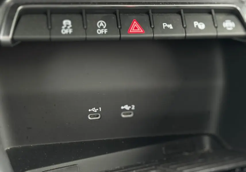Gros plan sur la console centrale noire de l'Audi A3 Berline 2024 avec deux ports USB-C et boutons de commande au-dessus.