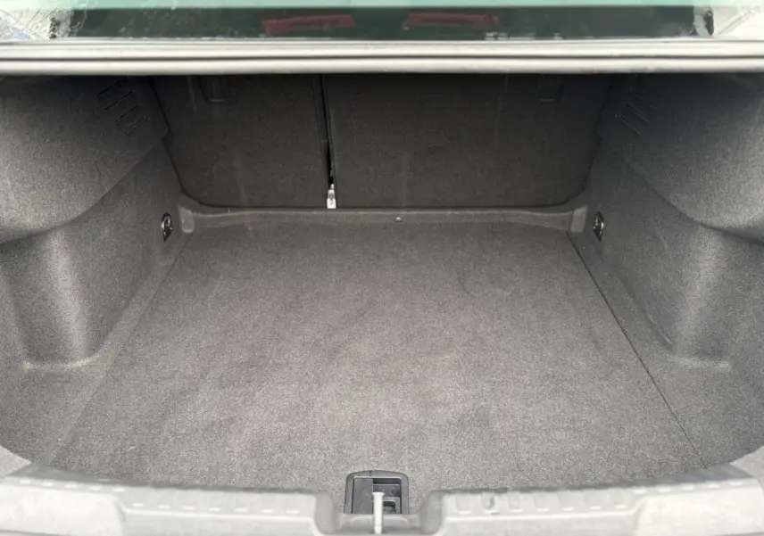 Coffre vide de l'Audi A3 Berline 2024 en vue intérieure, montrant le revêtement gris et l'espace de chargement.