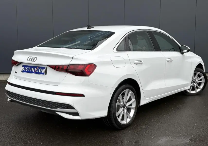 Audi A3 Berline blanc Arkona vue 3/4 arrière droit, jantes alliage 17 pouces et feux arrière LED distinctifs.