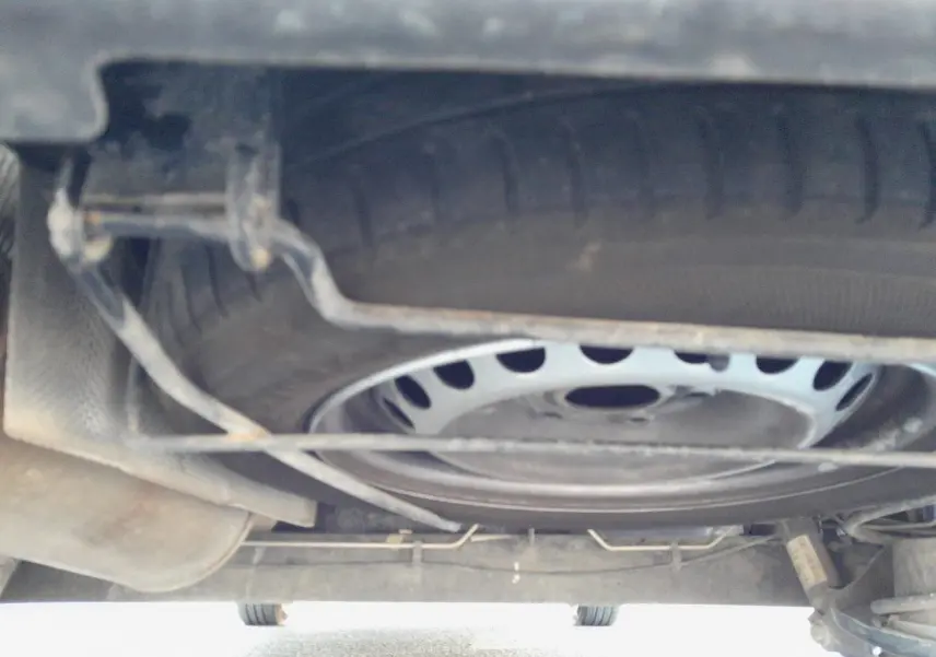 Vue sous le châssis du Renault Express Van blanc, montrant la roue de secours et les éléments de suspension.