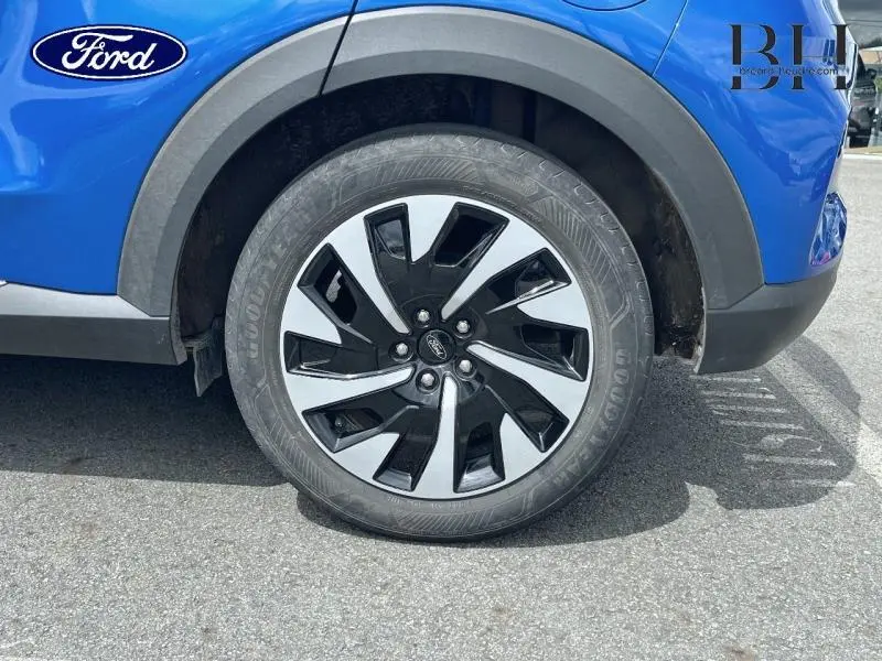 Gros plan sur la roue avant droite du Ford Puma 2022 bleu Fashion Island avec jante alu bicolore et logo Ford central.