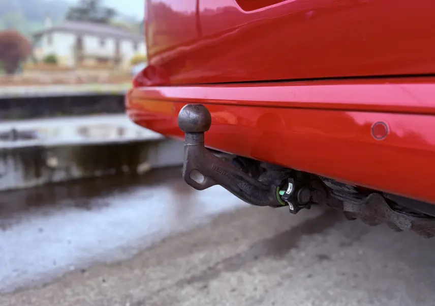 Gros plan sur l'attelage arrière noir d'un Volkswagen Transporter rouge, version 2017, avec pare-chocs et capteurs visibles.