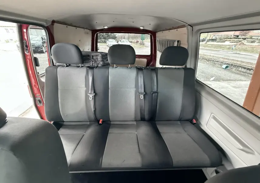Banquette arrière noire vue de l'intérieur du Volkswagen Transporter rouge, avec trois appuie-têtes et ceintures de sécurité.