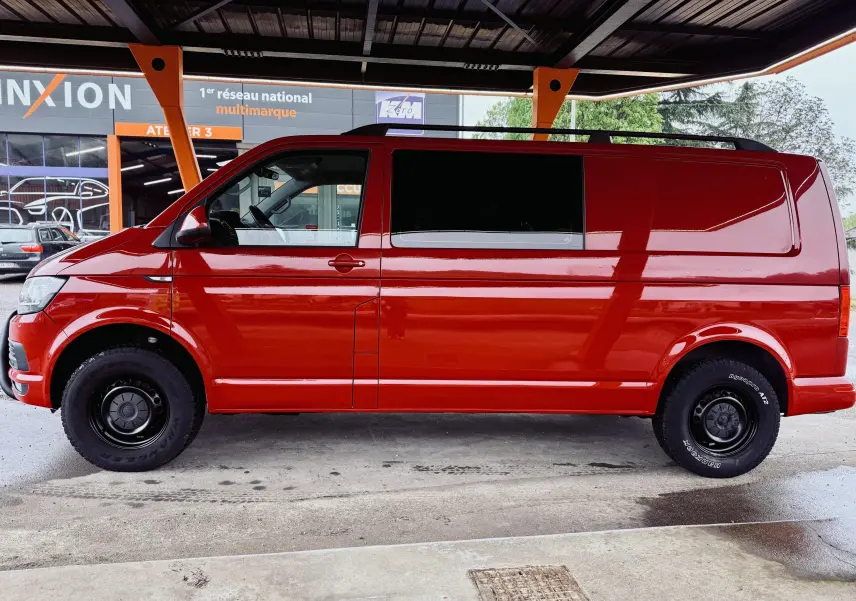 Vue de profil côté gauche du Volkswagen Transporter double cabine rouge, avec roues noires sous abri.