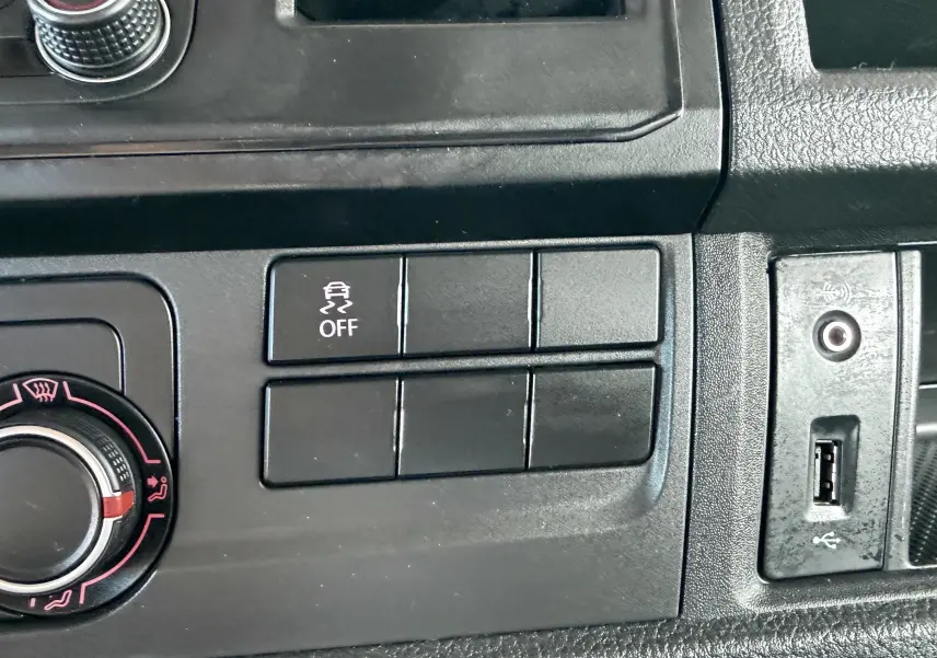 Détail du tableau de bord noir du Volkswagen Transporter rouge, avec bouton de contrôle de stabilité et prise USB visible.