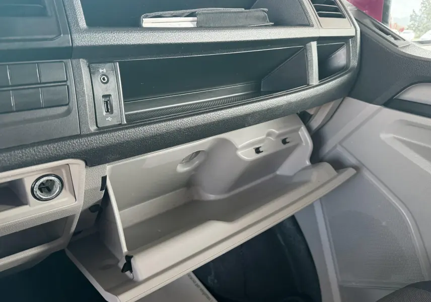 Intérieur du Volkswagen Transporter rouge 2017, vue du tableau de bord côté passager avec boîte à gants ouverte.
