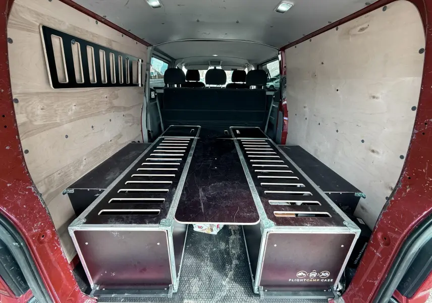 Vue arrière du Volkswagen Transporter rouge, aménagement intérieur avec caissons en bois et panneaux latéraux clairs.