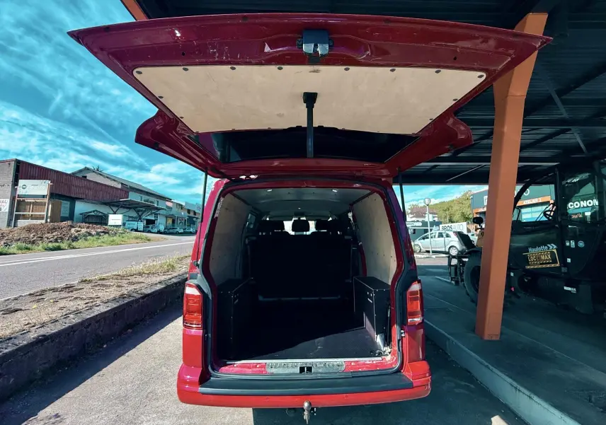 Vue arrière ouverte du Volkswagen Transporter rouge, montrant l’espace de chargement vide et le hayon relevé.