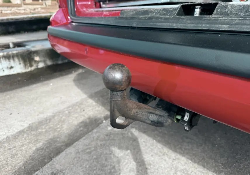 Gros plan sur l’attelage d’un Volkswagen Transporter rouge, vue arrière soulignant le pare-chocs et la boule d’attelage usée.