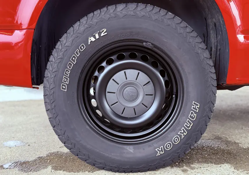 Gros plan sur la roue avant droite du Volkswagen Transporter rouge, pneu Hankook Dynapro AT2 tout-terrain visible.