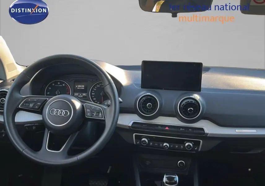 Intérieur d'Audi Q2 35 TFSI 2023, vue frontale du tableau de bord avec volant noir et écran central.
