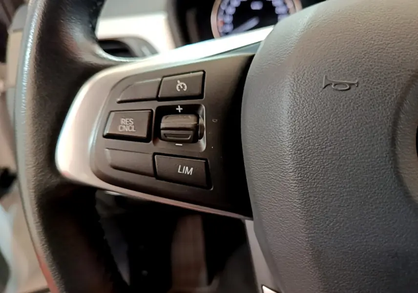 Gros plan sur les commandes de régulateur de vitesse au volant cuir du BMW X2 sDrive18i blanc 2023.