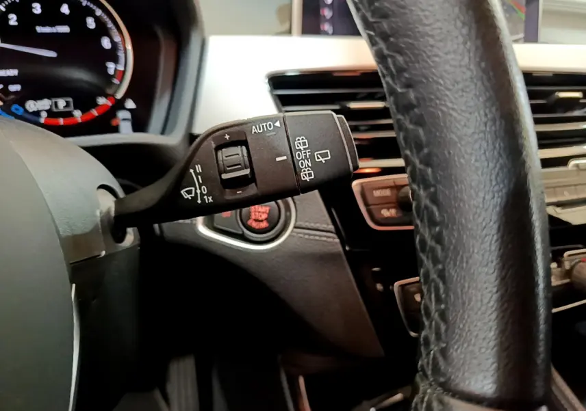 Gros plan sur la commande d’essuie-glace à gauche du volant cuir noir dans l’habitacle d’une BMW X2 blanc 2023.