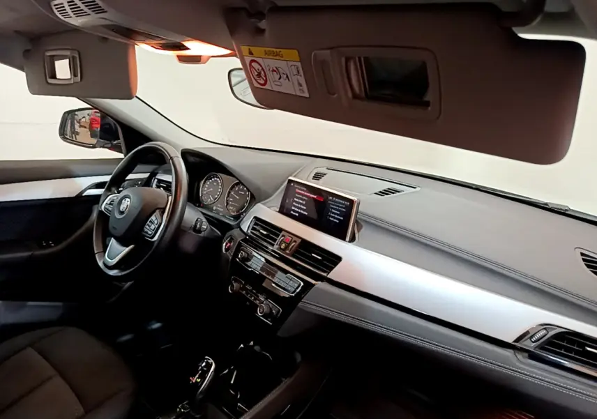 Vue intérieure côté conducteur du tableau de bord et volant cuir noir du BMW X2 sDrive18i 2023 avec écran central digital.