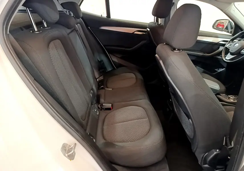 Vue intérieure côté gauche montrant les sièges arrière noirs et une partie du tableau de bord du BMW X2 blanc 2023.