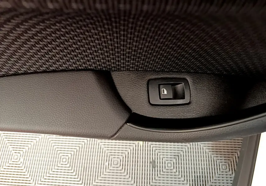 Bouton de verrouillage des portes sur la garniture intérieure noire d'une BMW X2 blanche, vue rapprochée côté porte.