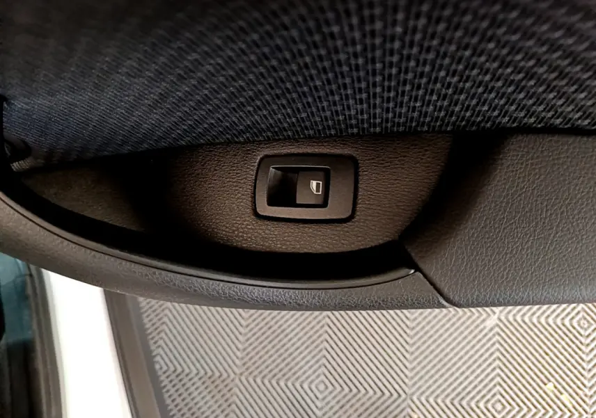 Bouton de commande de lève-vitre sur la portière côté gauche d'un BMW X2 blanc 2023, finition Business Design.